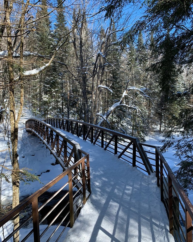 Un pont en bois enneigé qui enjambe une rivière