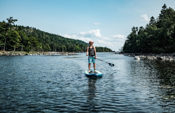 Stand-up paddle sur une eau translucide, entre une île et la côte