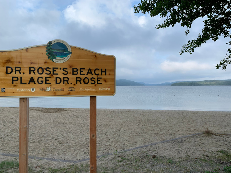 Un panneau 'plage du Dr Rose' au premier plan et la plage de Wawa derrière